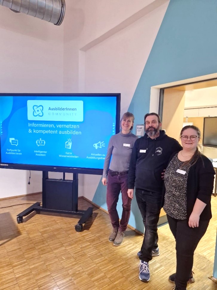 Drei Mitarbeiter:innen des Codips stehen neben einer digitalen Tafel. Diese zeigt die Funktionen der Online Plattform.